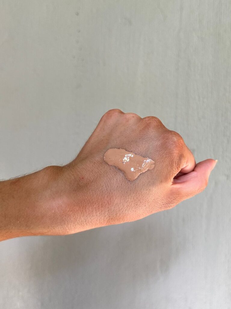 Hand testing skin-toned liquid foundation.