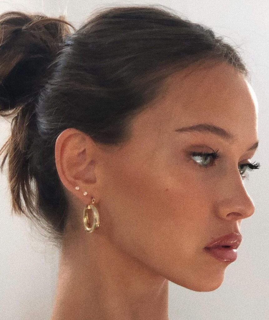 Woman with hoop earrings and subtle makeup.